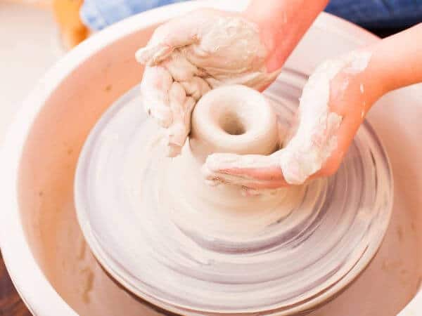 Mani di una persona mentre modella un pezzo di ceramica